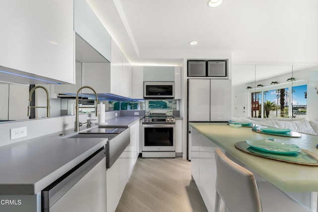 kitchen featuring sink, stainless steel appliances, light hardwood / wood-style floors, and white cabinets