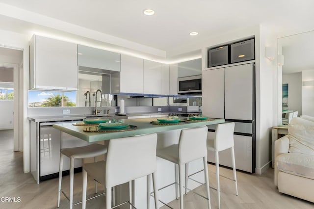 kitchen featuring white cabinetry, a kitchen bar, dishwasher, and sink