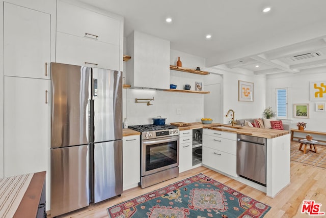 kitchen with sink, butcher block countertops, white cabinetry, light wood-type flooring, and appliances with stainless steel finishes