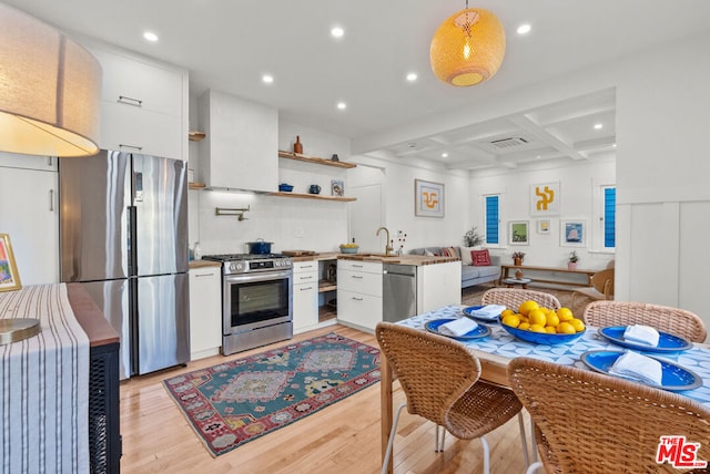 kitchen featuring appliances with stainless steel finishes, white cabinetry, coffered ceiling, beam ceiling, and light hardwood / wood-style flooring