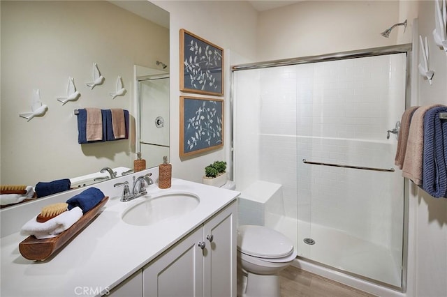 bathroom with an enclosed shower, vanity, hardwood / wood-style flooring, and toilet