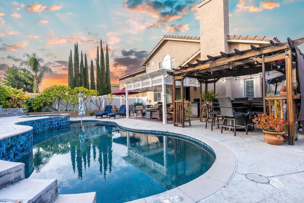 pool at dusk featuring a patio, exterior bar, and a pergola