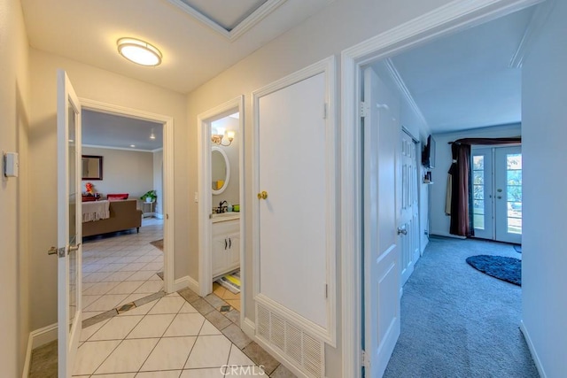 hallway with ornamental molding and light tile patterned floors