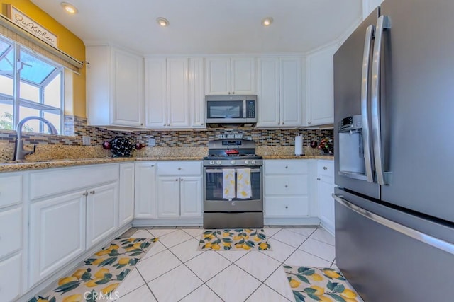 kitchen featuring light stone countertops, stainless steel appliances, and white cabinets