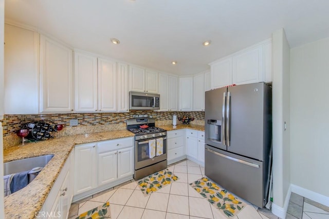 kitchen featuring white cabinetry, stainless steel appliances, light stone counters, and light tile patterned floors