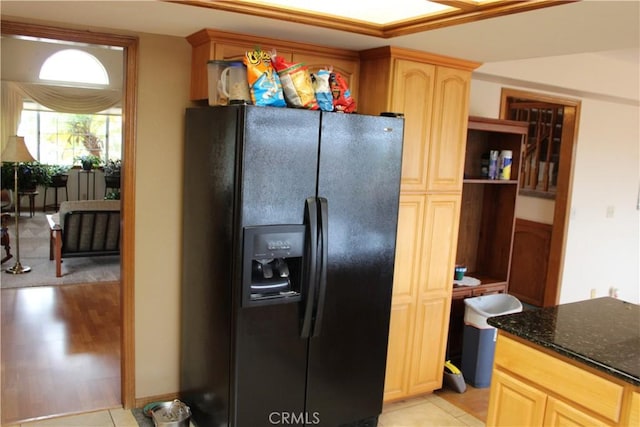 kitchen with light tile patterned flooring, light brown cabinetry, black fridge with ice dispenser, and dark stone counters