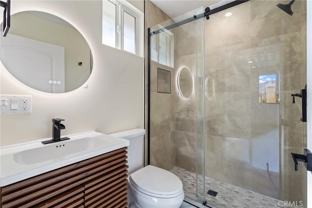 bathroom featuring vanity, a shower with shower door, and toilet