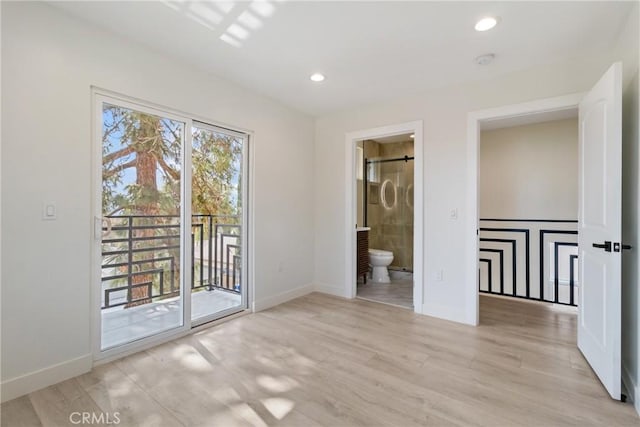 unfurnished bedroom featuring access to outside, ensuite bath, and light hardwood / wood-style flooring