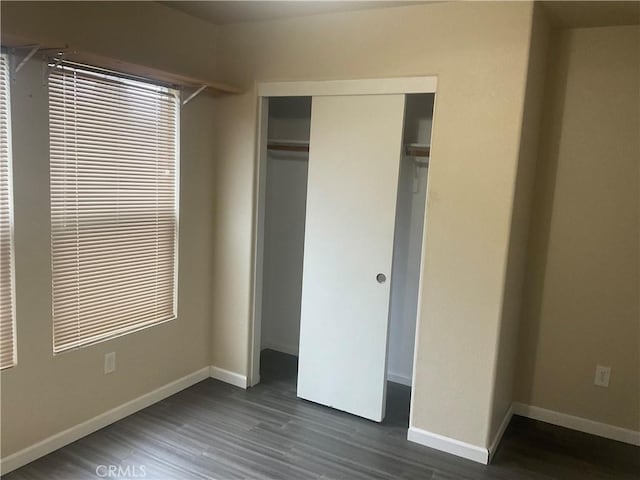 unfurnished bedroom with dark hardwood / wood-style floors and a closet