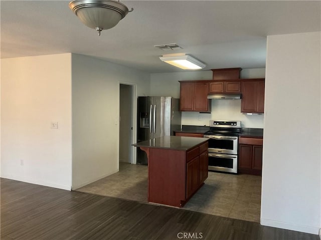 kitchen with a breakfast bar, stainless steel appliances, a kitchen island, and dark hardwood / wood-style flooring