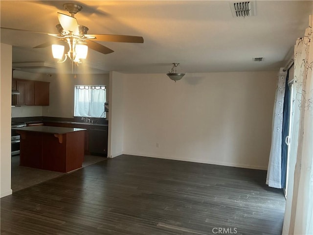 kitchen featuring sink, stove, a center island, ceiling fan, and dark wood-type flooring