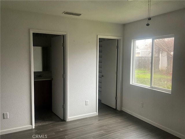 unfurnished bedroom with hardwood / wood-style flooring and connected bathroom