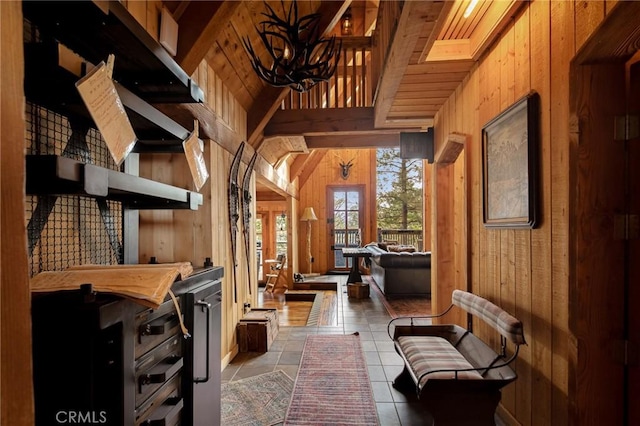 corridor with tile patterned flooring, wooden walls, vaulted ceiling, wooden ceiling, and a chandelier