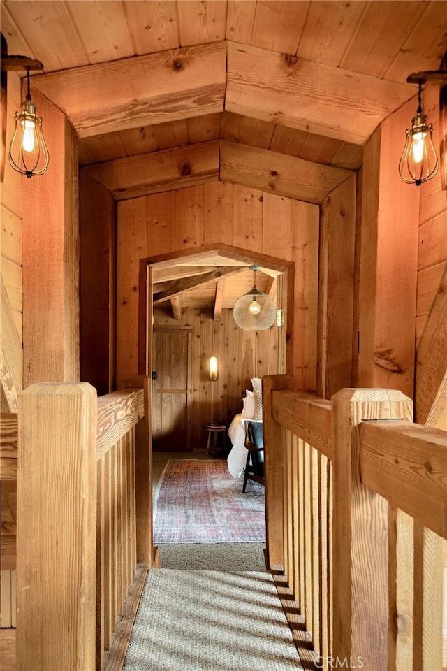 hall with lofted ceiling with beams, wooden ceiling, and wood walls