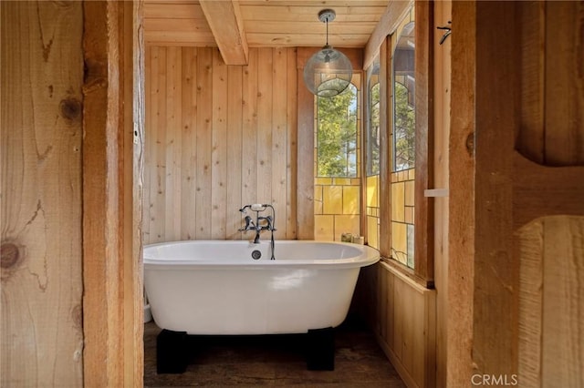 bathroom with wood ceiling, beam ceiling, a bathtub, and wood walls