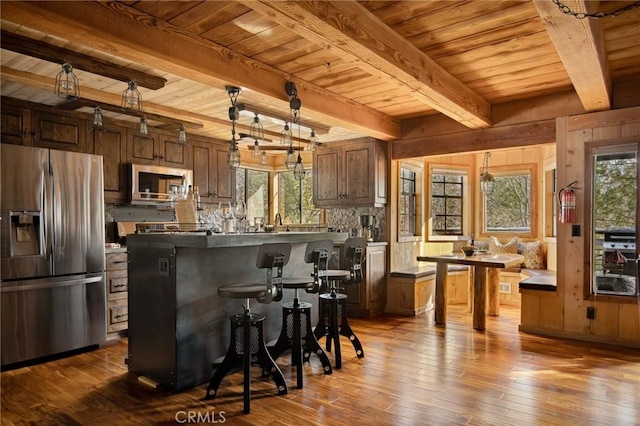 kitchen with decorative light fixtures, wood-type flooring, a center island, wood ceiling, and stainless steel appliances