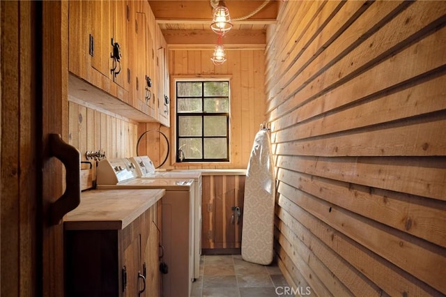 washroom featuring washer and dryer, cabinets, and wood walls