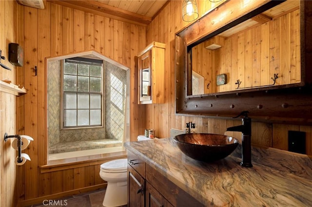 bathroom with wooden walls, a tub to relax in, vanity, toilet, and wooden ceiling