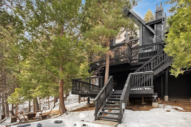 snow covered back of property with a wooden deck