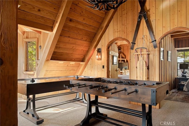 rec room with vaulted ceiling with beams, wood ceiling, carpet flooring, and wood walls