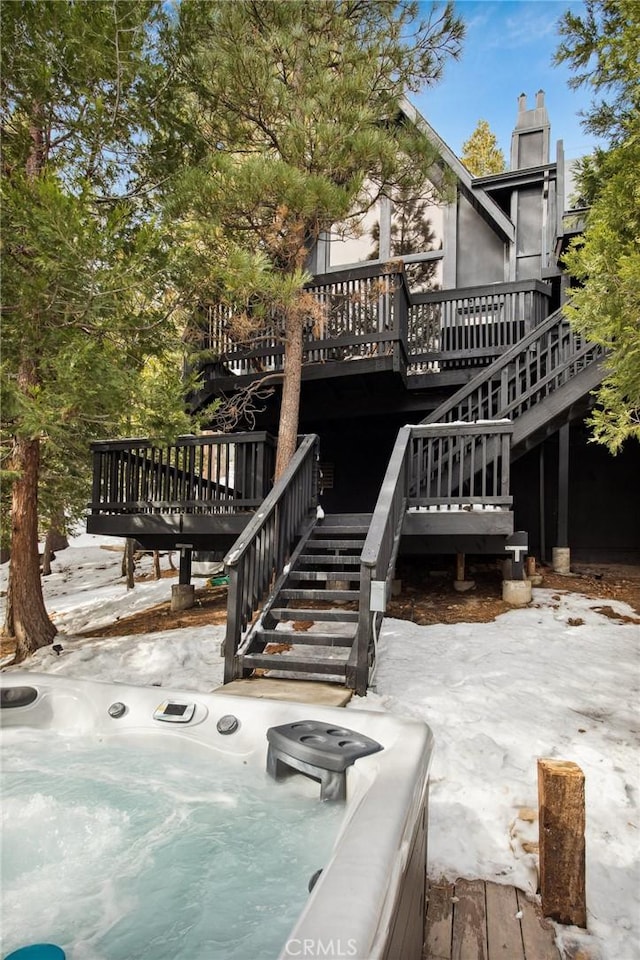 back of property with a hot tub and a deck