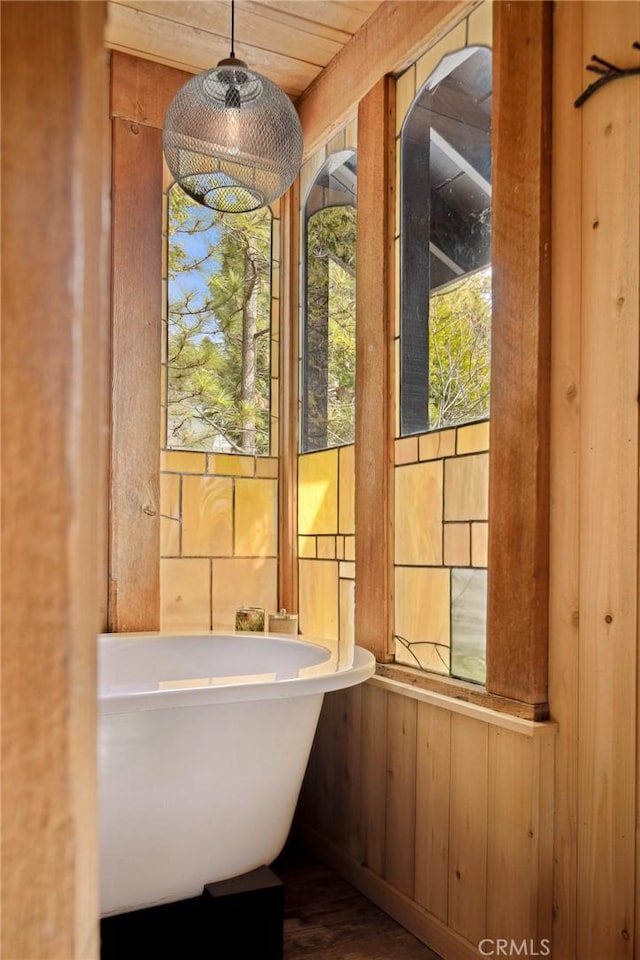 bathroom featuring a tub to relax in and wood walls