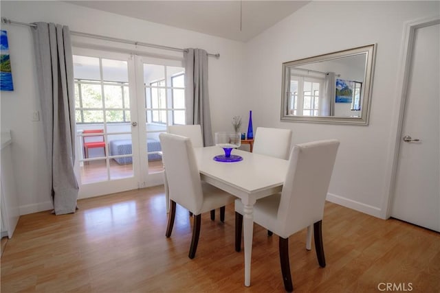 dining room with light hardwood / wood-style flooring, french doors, and vaulted ceiling