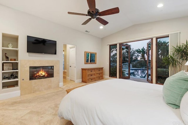 carpeted bedroom featuring ceiling fan, lofted ceiling, a tiled fireplace, and access to outside