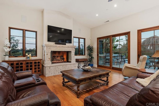 living room featuring high vaulted ceiling, a high end fireplace, and light hardwood / wood-style floors