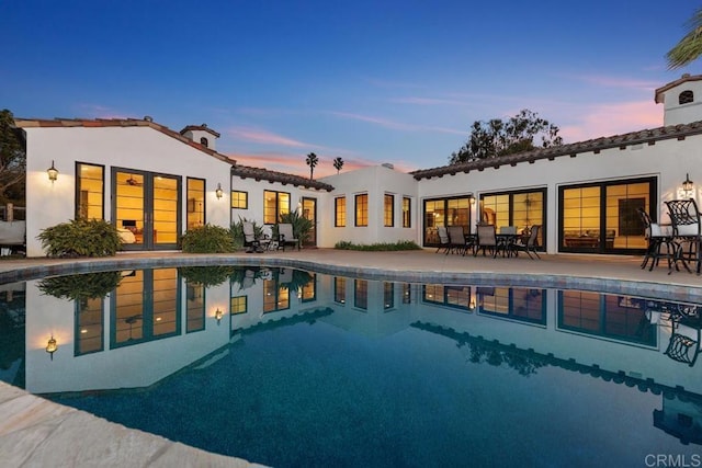 pool at dusk featuring a patio