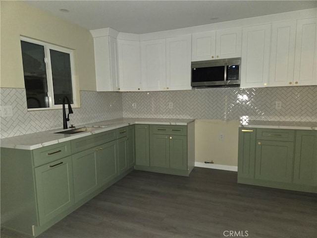 kitchen with green cabinetry, sink, and white cabinets