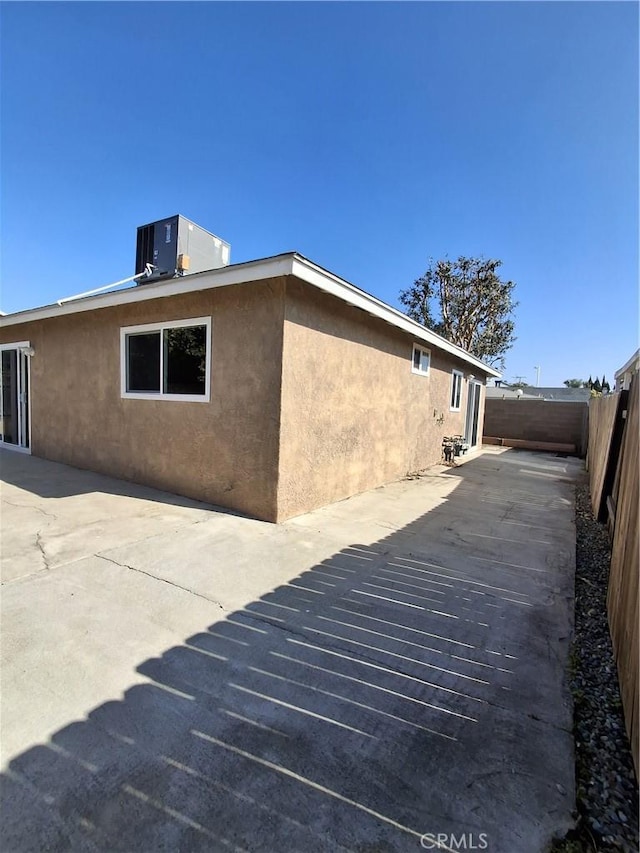 view of side of property with a patio area and central air condition unit