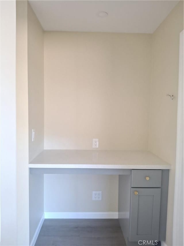 unfurnished office featuring dark hardwood / wood-style flooring and built in desk