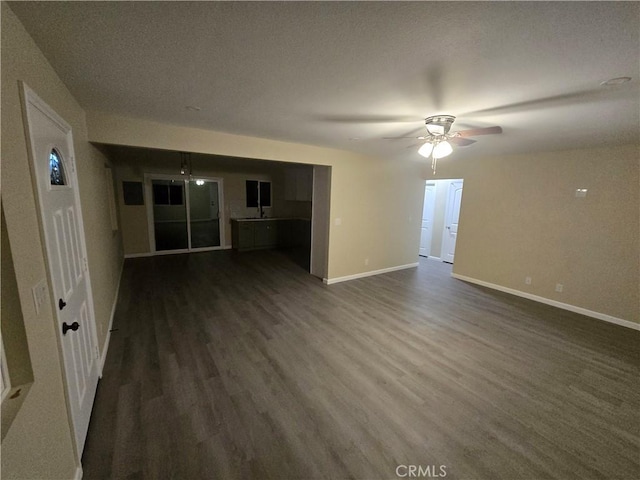 unfurnished living room with dark hardwood / wood-style flooring and ceiling fan