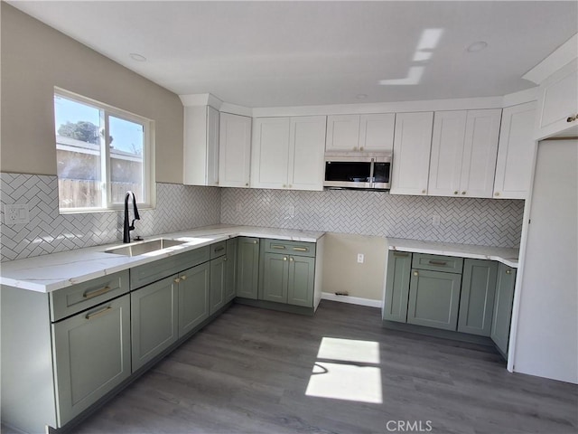 kitchen featuring sink, white cabinets, decorative backsplash, light stone countertops, and dark wood-type flooring