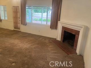 unfurnished living room with dark carpet and a brick fireplace