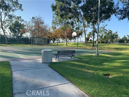 view of home's community featuring basketball court and a lawn