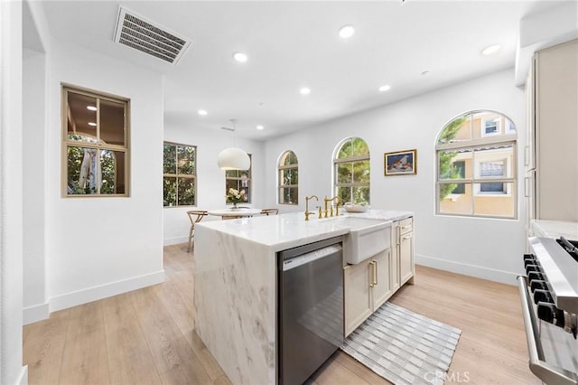 kitchen with sink, stainless steel appliances, an island with sink, and light wood-type flooring