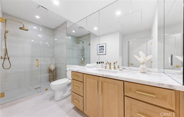 bathroom with a shower with door, vanity, and toilet