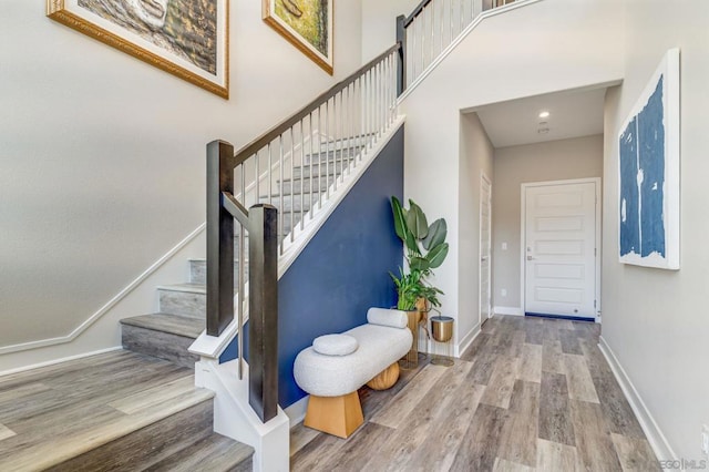 stairs with a towering ceiling and hardwood / wood-style floors