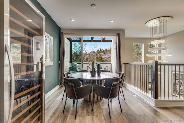 dining room with light wood-type flooring, beverage cooler, and a chandelier