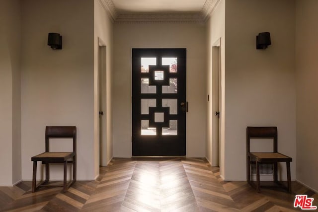 entryway with ornamental molding and parquet flooring