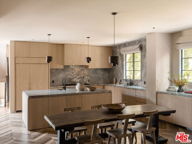 kitchen with sink, light parquet floors, a kitchen island, decorative backsplash, and light brown cabinets