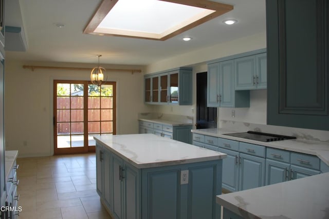 kitchen with black electric cooktop, a skylight, decorative light fixtures, and a center island