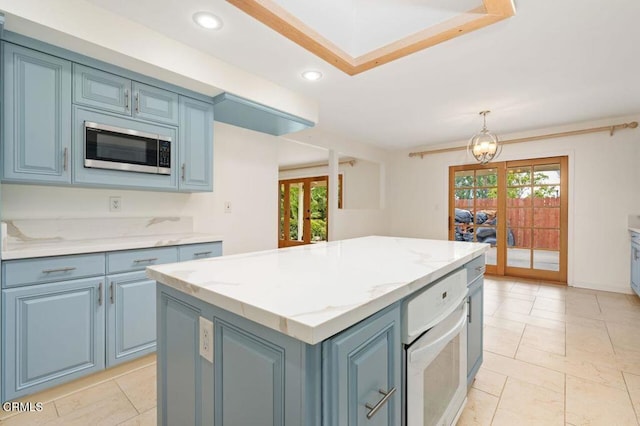 kitchen featuring french doors, blue cabinetry, light stone counters, decorative light fixtures, and a kitchen island