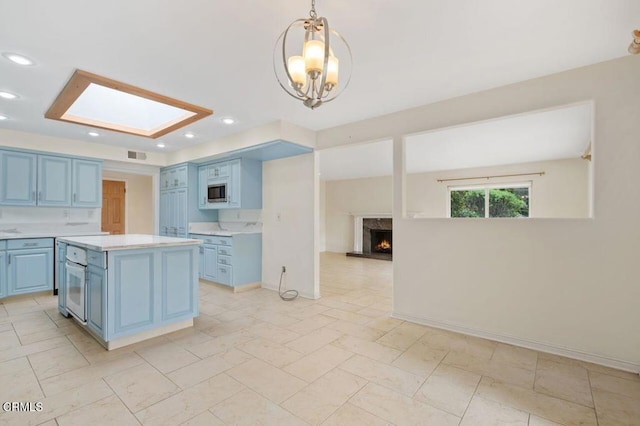 kitchen featuring a skylight, a kitchen island, a high end fireplace, blue cabinets, and decorative light fixtures