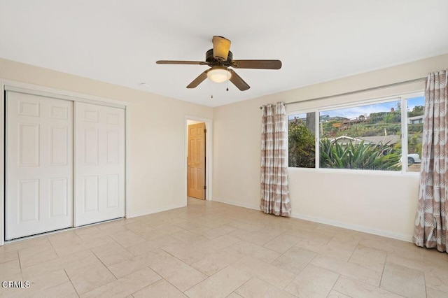 unfurnished bedroom with ceiling fan and a closet