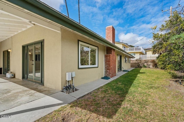 view of side of property featuring a lawn and a patio