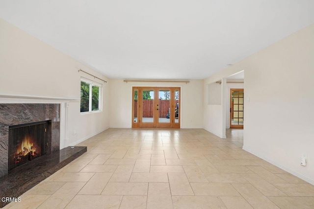 unfurnished living room with a high end fireplace and french doors