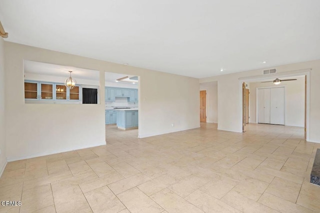 spare room with ceiling fan with notable chandelier